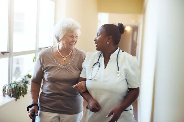 Nurse walking a senior citizen down a hall for senior living marketing