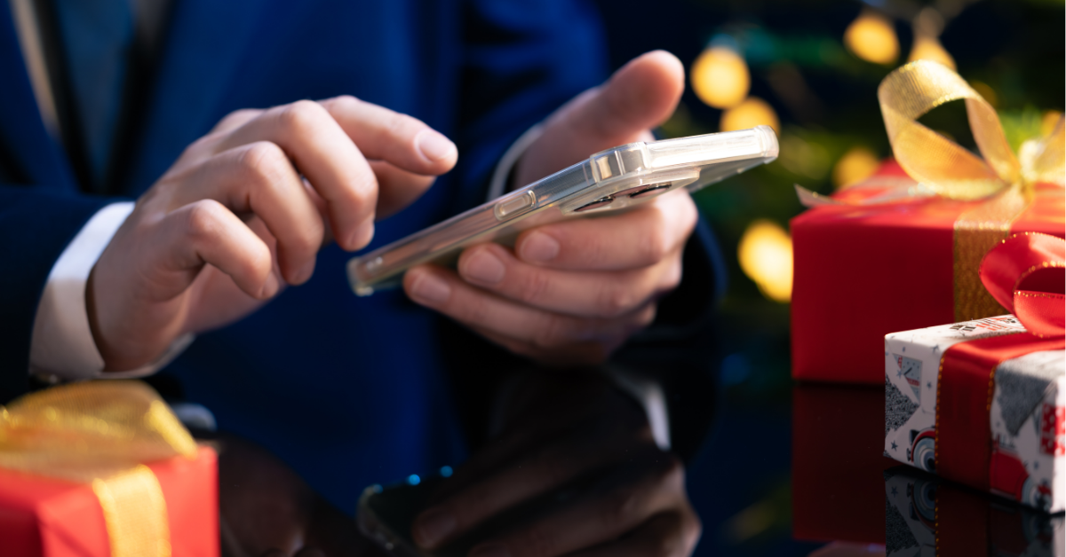 A closeup on a man's hands and cell phone as he shops online for holiday gifts.
