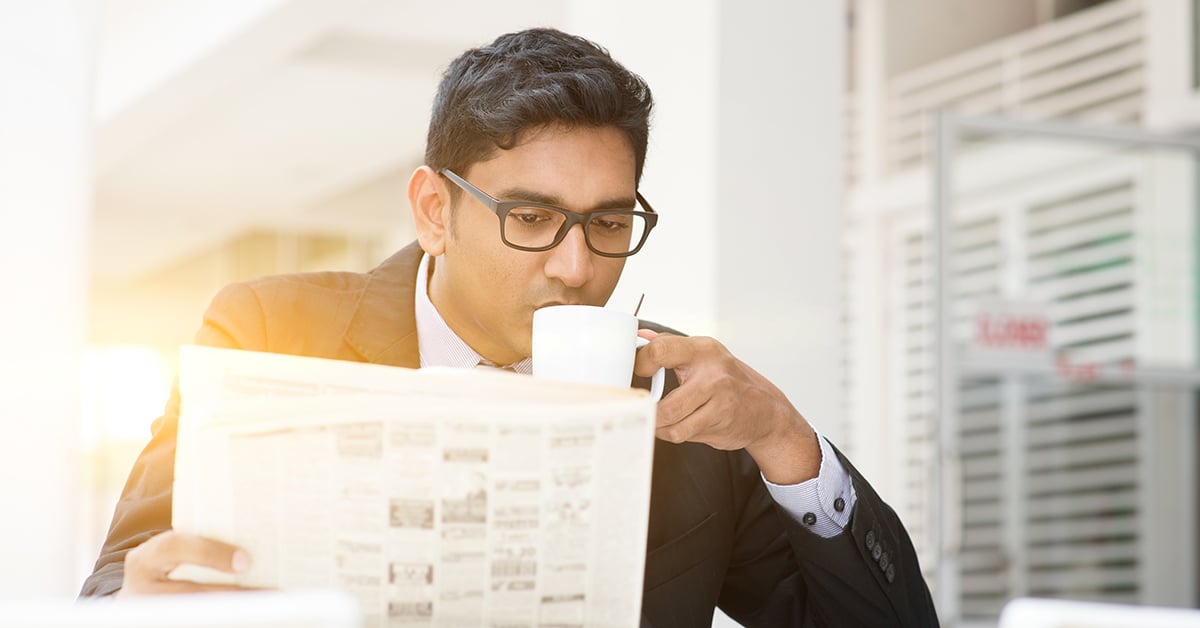 A man reads the newspaper with his morning coffee.
