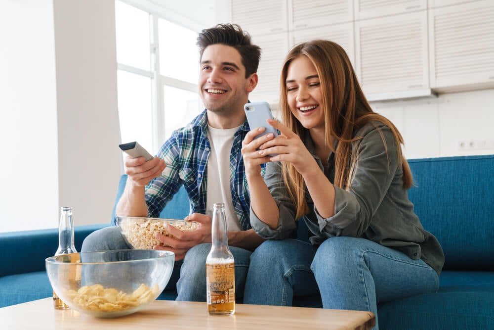 Couple watching TV while checking smartphone