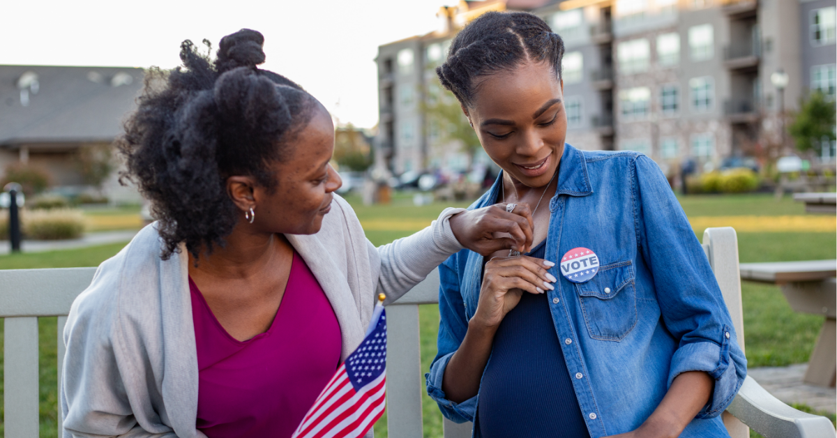 Two women, one pregnant, wear "I voted" stickers on election day.